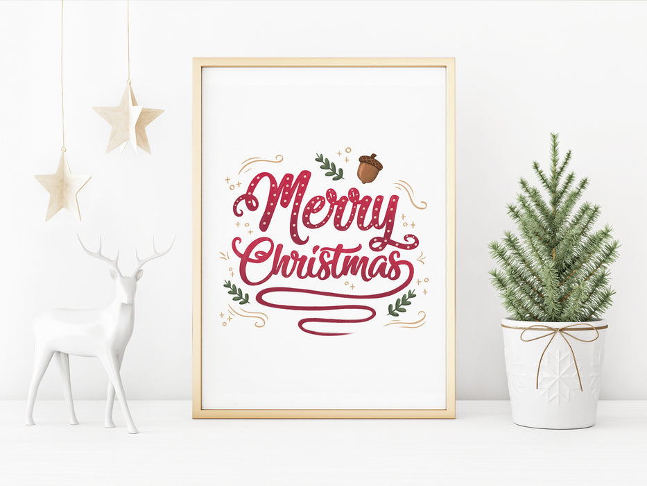 gold framed merry christmas typography print surrounded by holiday decor such as a gold hanging stars, a white deer statue, and a mini pine tree in a white plant pot