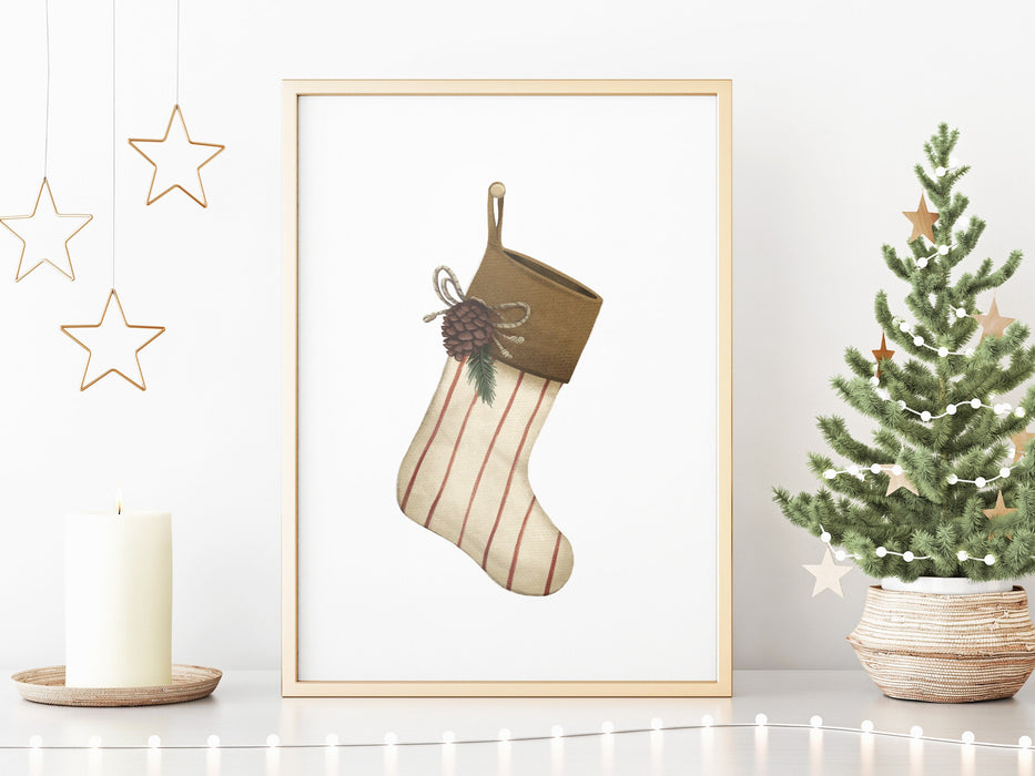 gold framed Christmas print with a rustic stocking surrounded by gold holiday decor such as a candle, gold stars, and a mini tree decorated with stars and mini lights