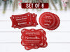 Text reads, Set of 6. Six red glitter cardstock Santa gift tags are shown on a white wooden surface. Pine tree branches, pine cones, and other foliage can be seen on the top of the image.