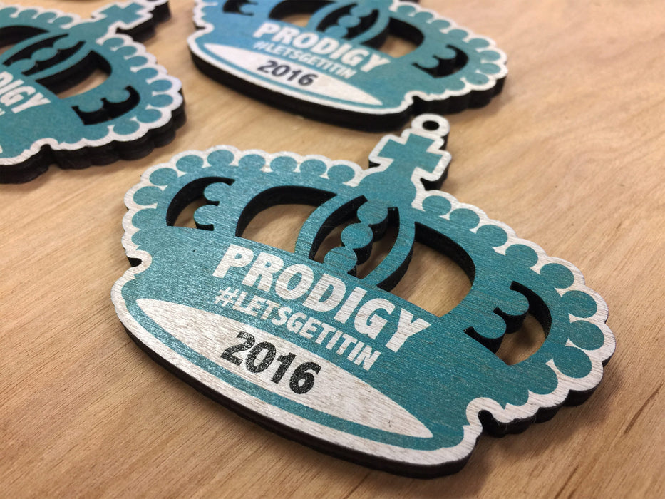 Custom blue and white crown ornament is shown on a wooden surface. The text, Prodigy #Letsgetitin 2016, are printed on ornament.