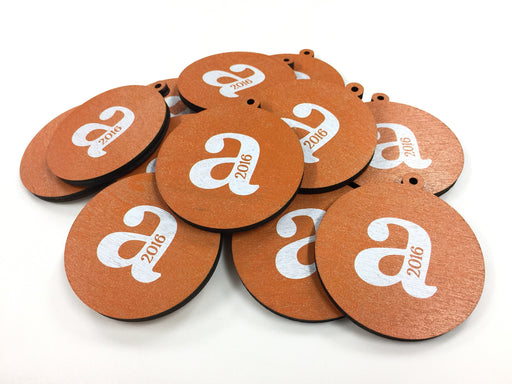 Multiple custom printed ornaments are shown with the letter A and 2016 printed in white and orange. Ornaments are shown on a white surface.