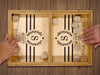 puck sling board game with an S monogram with wreath design that reads The Scott Family on wooden table with two hands playing with wooden puck discs