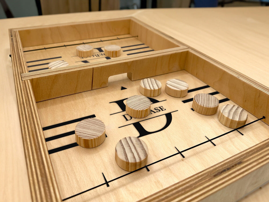 puck sling board game with an initial last name design that reads the letter D and says the name DeBaise with wooden discs on wooden table