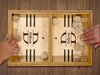 puck sling board game with an initial last name design that reads the letter D and says the name DeBaise with two hands playing with wooden discs on wooden table