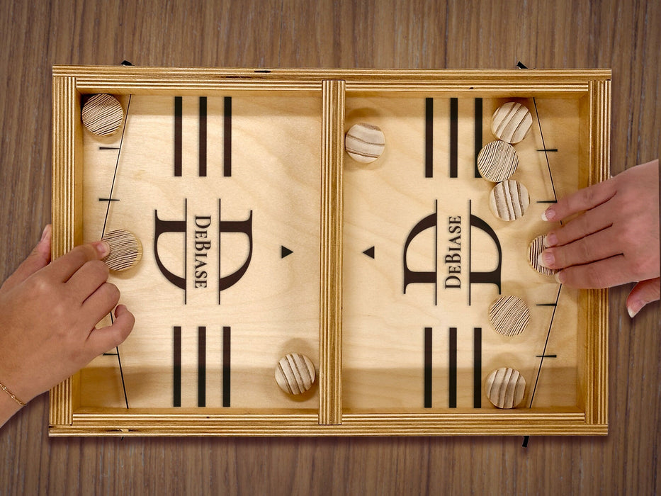 puck sling board game with an initial last name design that reads the letter D and says the name DeBaise with two hands playing with wooden discs on wooden table