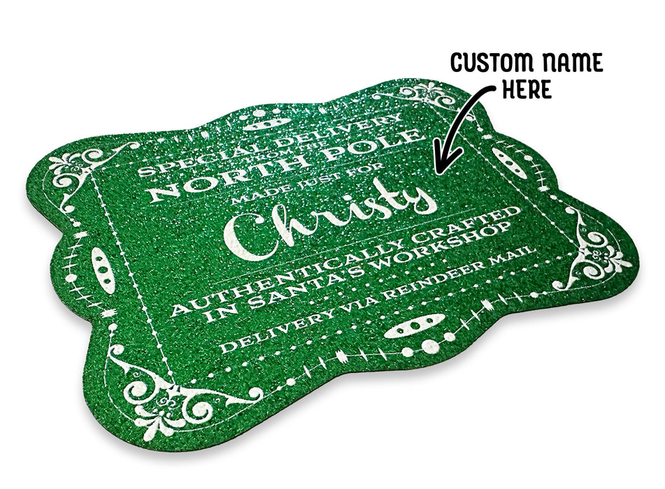A green glitter cardstock Santa gift tag is shown on a white surface. The text above it reads, Custom Name Here.
