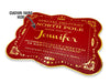 A gold foil cardstock Santa gift tag is shown on a white surface. The text above it reads, Custom Name Here.