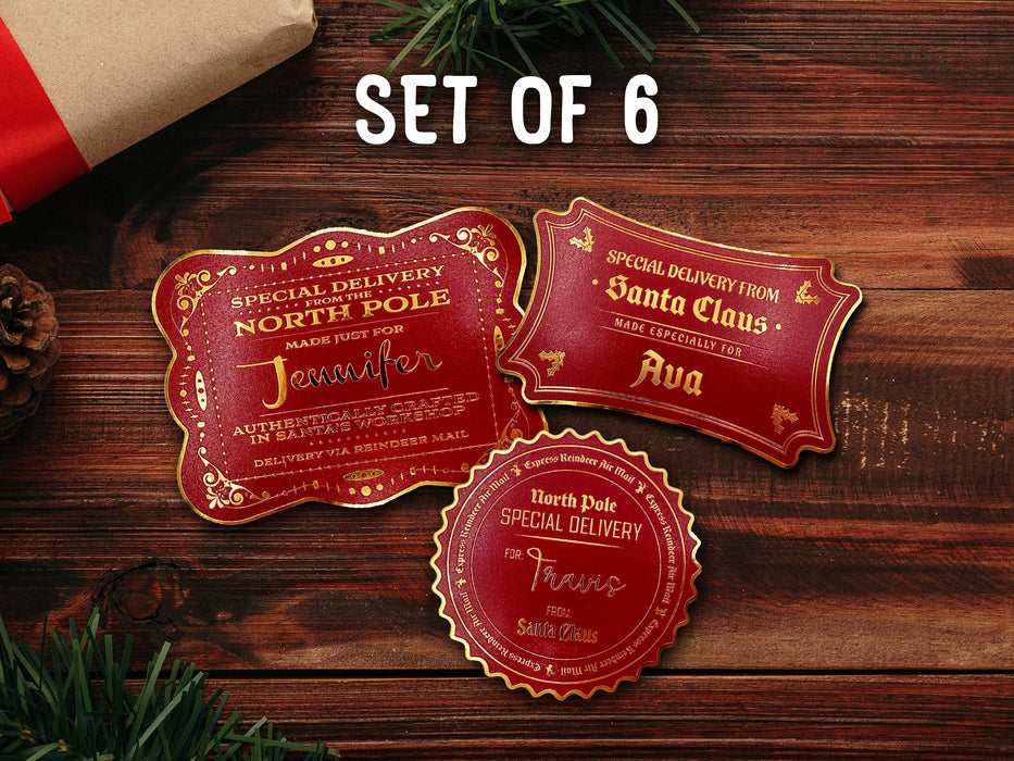 Text reads, Set of 6. Three gold foil cardstock Santa gift tags are shown on a dark wooden surface. Pine tree branches, a pine cone, a red ornament, and a Christmas present are shown around the tags.