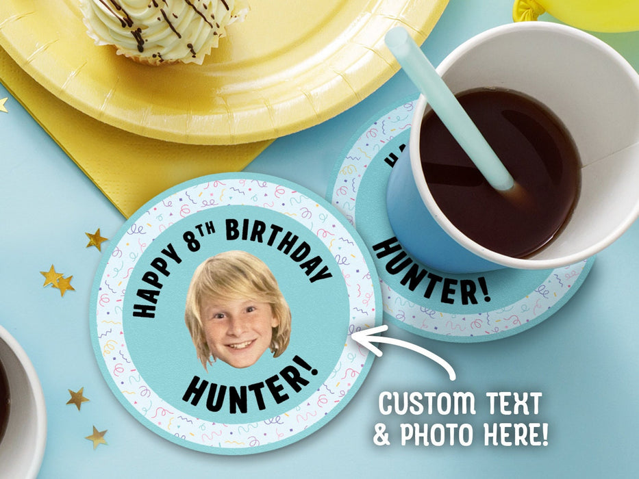 One coaster has a drink on it and an empty coaster sits beside it on a decorated table. Coasters are designed with multi-colored confetti, teal blues, and a custom face photo. Coaster text reads Happy 8th Birthday Hunter!