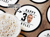 Coasters are on a wooden surface with a beer in the left bottom corner. Coasters are shown with custom face and text design. Coasters read Happy 30th Kyle! Coasters are designed with black text and a custom face photo.