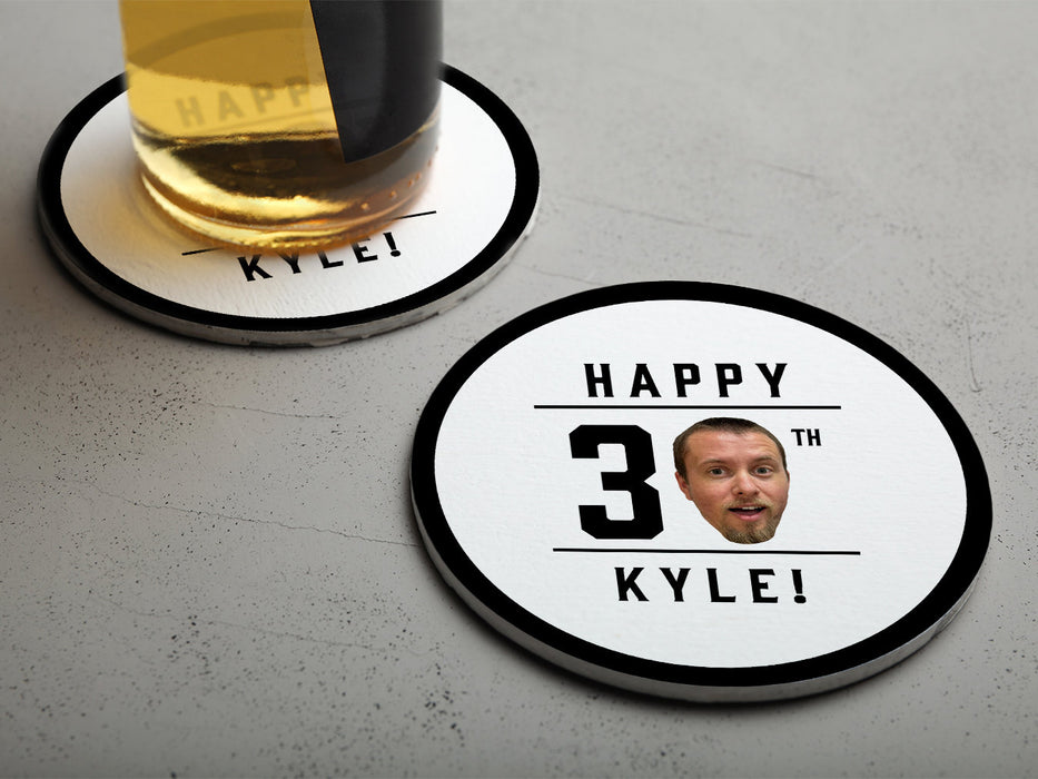 One empty coaster is shown with a beer glass on a second coaster. Coasters are shown with custom face and text design. Coasters read Happy 30th Kyle! Coasters are designed with black text and a custom face photo.