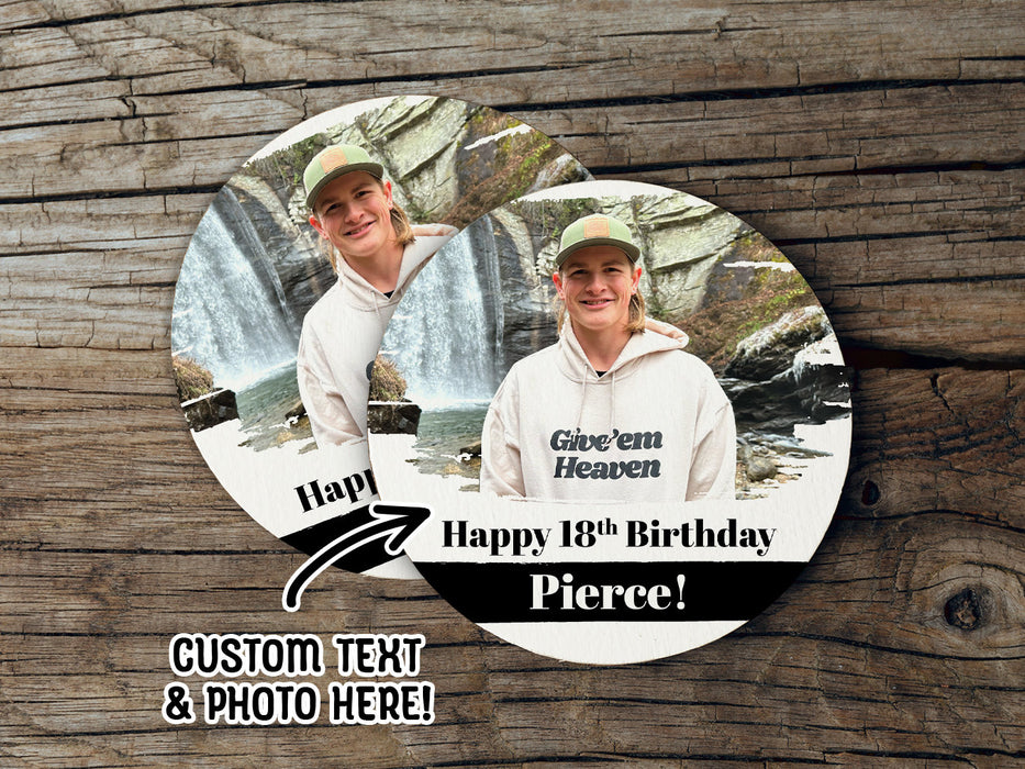 Two coasters sit on a wooden surface. Coasters shown are customizable. Coasters are designed with custom photo, text, and brushed elements. Coaster text reads Happy 18th Birthday Pierce!