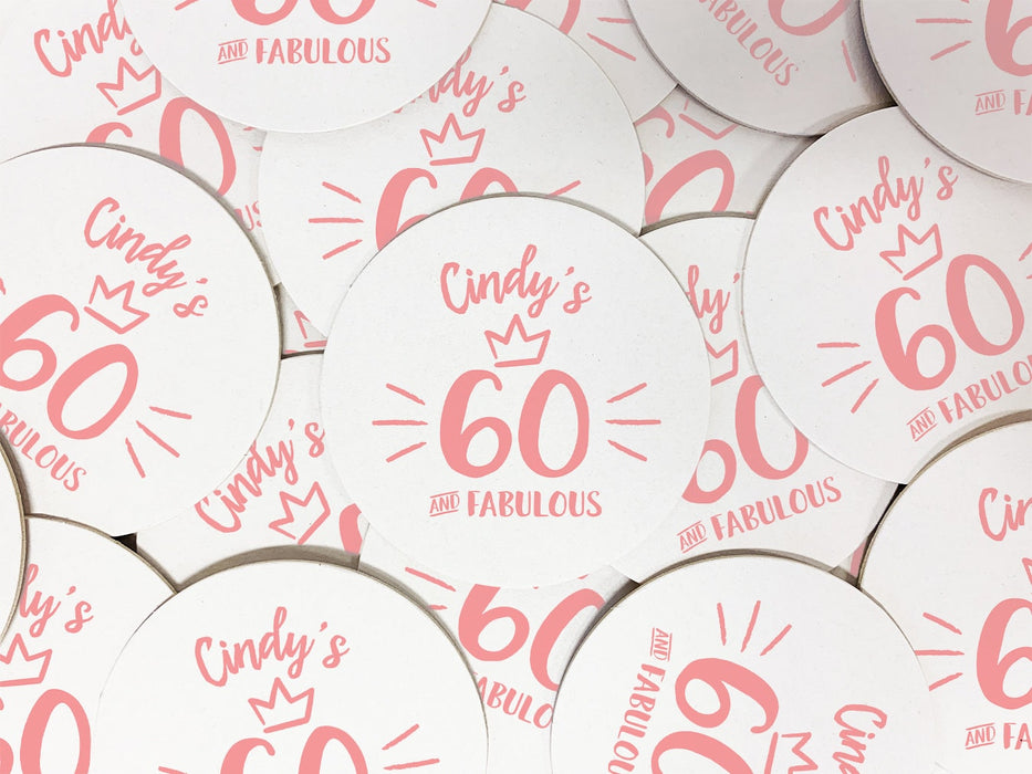 Multiple coasters are spread out on a flat surface. Coasters are designed with pink ink. Coaster text reads Cindy's 60 and Fabulous.