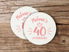 Two coasters are shown on a wooden surface. Coasters are designed with pink ink. Coaster text reads Melanie's 40 and Fabulous.