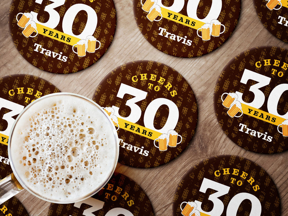 Multiple coasters shown on a wooden surface with a beer mug. Coasters say Cheers to 30 Years, Travis!