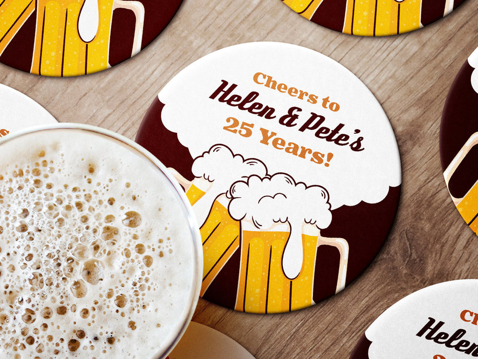 Multiple coasters shown on a wooden surface with a beer mug. Coasters show cheersing beer glasses and say Cheers to Helen & Petes 25 Years!