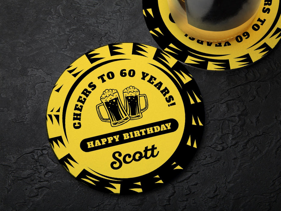 One coaster has a drink on it and an empty coaster sits beside it on a black background. Coasters say Cheers to 60 Years! Happy Birthday Scott.
