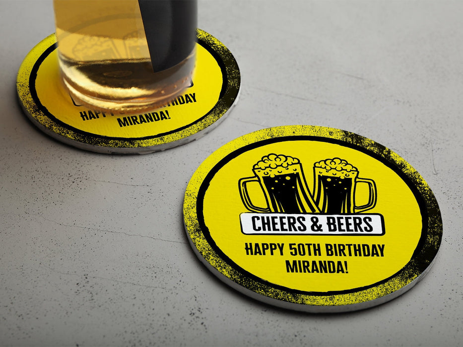 One coaster has a drink on it and an empty coaster sits beside it on a grey background. Coasters say Cheers & Beers, Happy 50th Birthday Miranda!