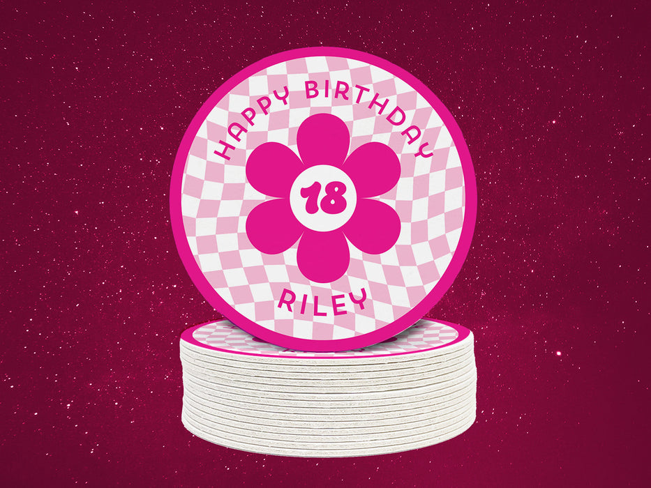 A single coaster is shown on top of a stack of coasters with a pink starry background behind. Coasters are designed with hot and light pink ink. Coaster text reads Happy Birthday Riley with the number 18 in the center of a pink flower.