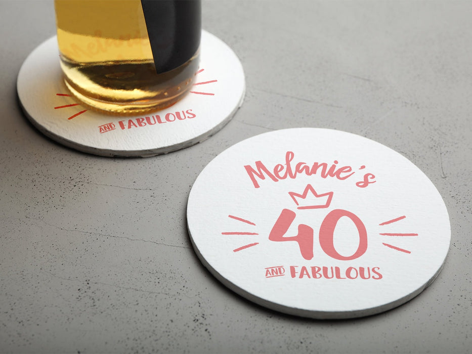 One empty coaster is shown with a beer glass on a second coaster. Coasters are designed with pink ink. Coaster text reads Melanie's 40 and Fabulous.