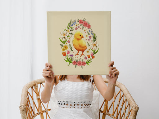 woman in white dress in a wicker chair holding a 12x12 inch canvas with spring easter chick pastel easter art in white living room