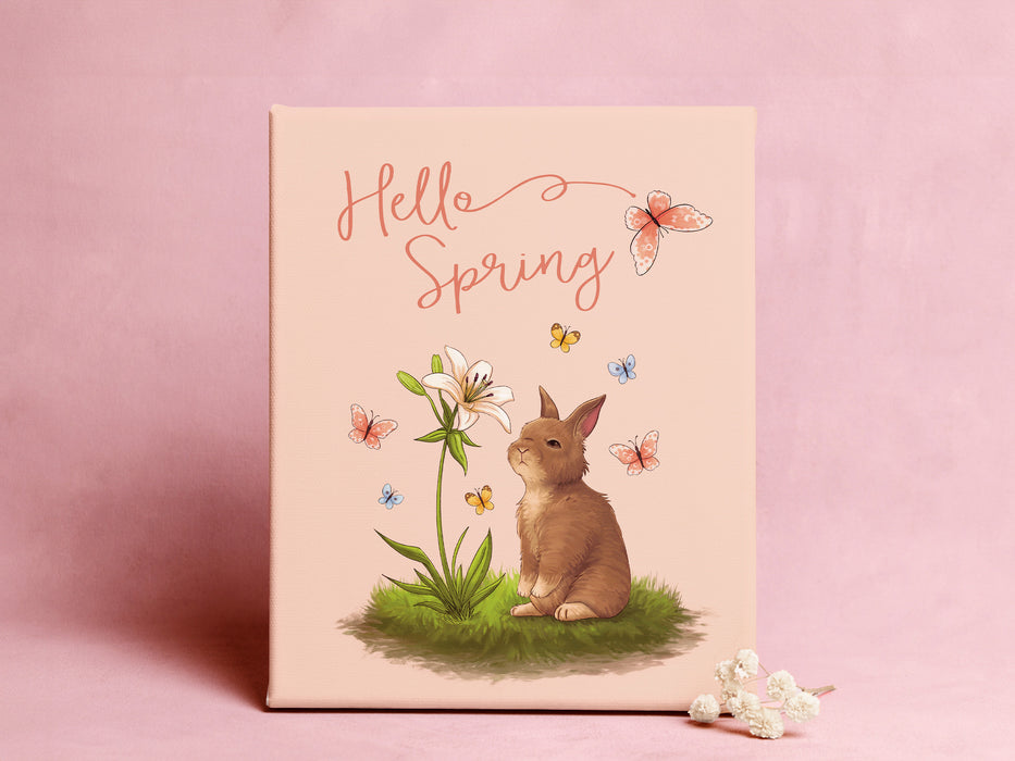 12x12 canvas with Hello Spring Easter print with a bunny and butterflies in front of a purple wall with small flowers in front of the canvas