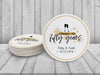 A stack of coasters by a single coaster on a white wooden surface. Coasters shown are customizable. Coasters are designed with gold sparkly elements, wine glasses, and the words Cheers to fifty years, custom names, and custom date.
