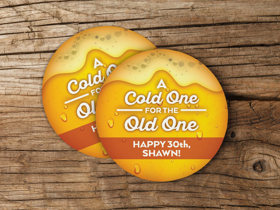 Two coasters are shown on a wooden surface. Coasters say A Cold One for the Old One, Happy 30th, Shawn!