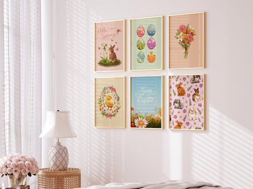 Set of 6 easter prints with pastel spring artwork such as flowers, plants, chicks, eggs, and bunnies  on white living room wall nearby a bed, a white lamp on a side table, and pink potted roses