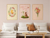 three easter prints with pastel easter artwork in wooden frames on white living room wall surrounded by household furniture such as a white couch, throw pillows, coffee table, etc