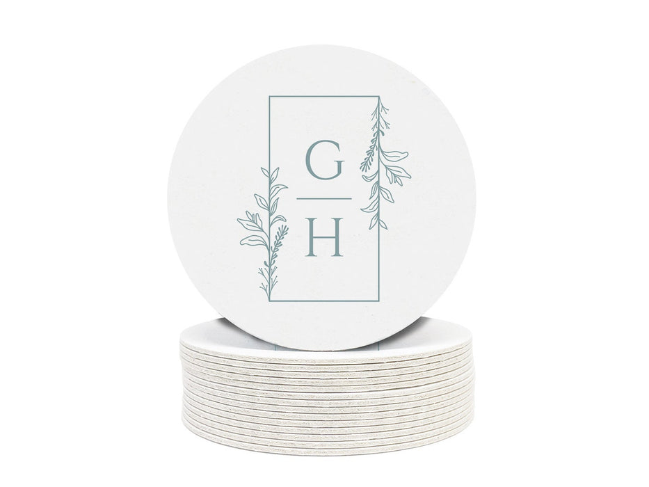 A stack of round coasters with the letters GH and a floral frame on them against a white background.