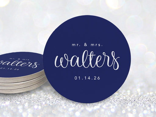 A stack of coasters by a single coaster in front of glittery background. Coasters feature a custom last name design with a married couple's last name and wedding date.