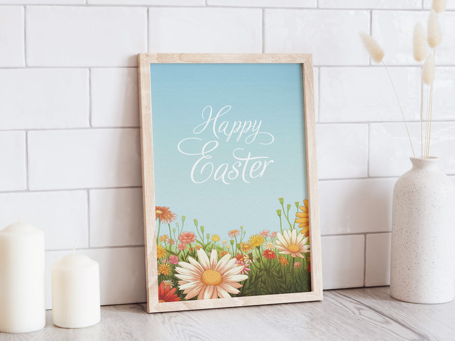 wooden frame with happy easter print with a colorful meadow of spring flowers on a white kitchen counter top surrounded by candles and a potted plant