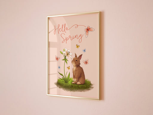 pastel easter print that says hello spring with a bunny and a lily surrounded by colorful butterflies in a gold frame on living room pink wall