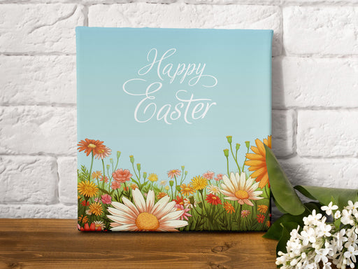 12x12 canvas of happy easter artwork of a spring meadow on a wooden table next to a small bouquet of white flowers in front of a white brick wall
