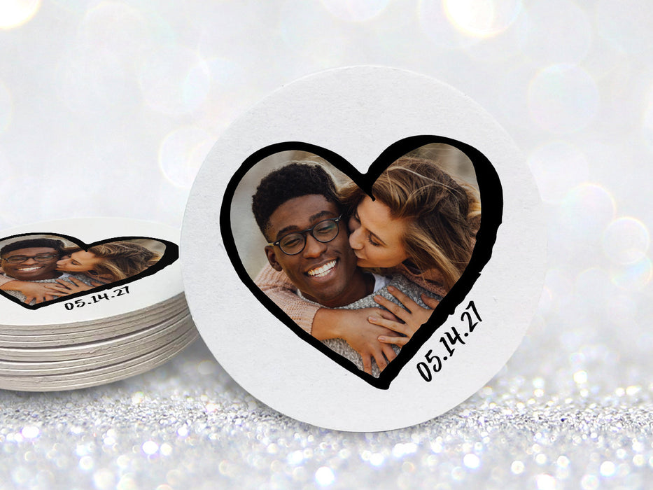 A stack of coasters by a single coaster on a glitter background. Coasters shown are customizable. Coasters are designed with custom photo, text, and sketched heart frame. Coaster text reads 05.14.27