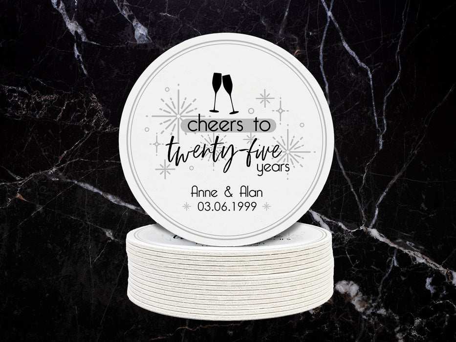 One coaster sits on top of a stack of coasters with a black marble background. Coasters shown are customizable. Coasters are designed with gray sparkly elements, wine glasses, and the words Cheers to twenty-five years, custom names, and custom date.