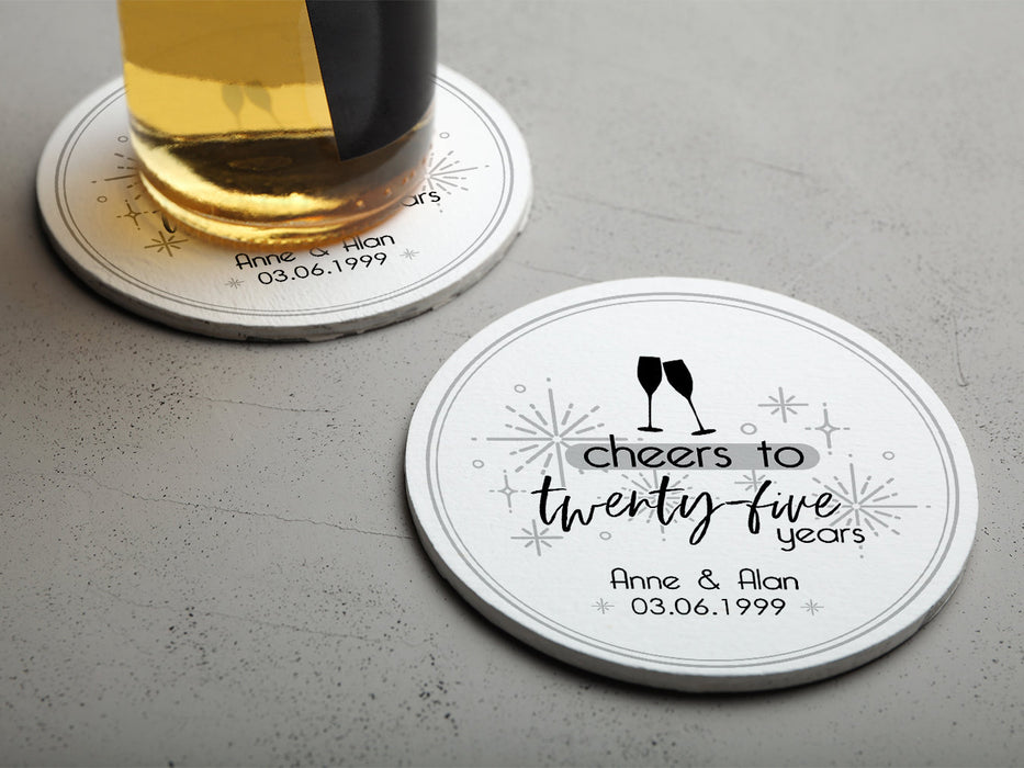 One coaster has a beer glass on top and the other is empty on a table. Coasters shown are customizable. Coasters are designed with gray sparkly elements, wine glasses, and the words Cheers to twenty-five years, custom names, and custom date.