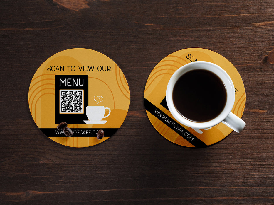 wooden table with a cup of coffee with two custom round QR code coasters that say Scan to view our menu, www.ACGCAFE.com