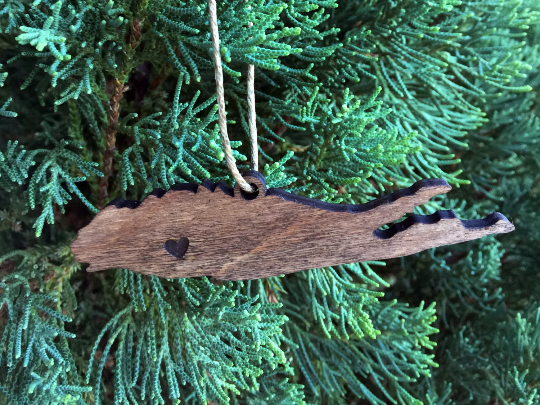 Ornament shown hanging from Christmas tree. This ornament is made out of wood and is shaped as Long Island, New York. A heart is laser etched where chosen hometown or city would be.